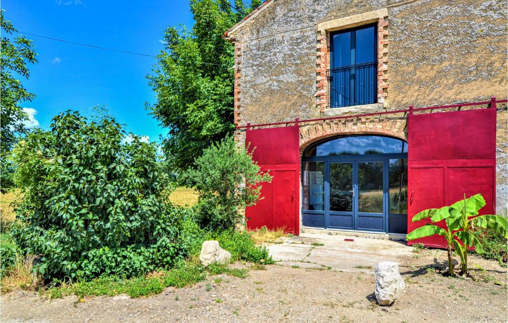 un ancien bâtiment avec une porte rouge et une fenêtre dans l'établissement Cozy Home In Mornas With Kitchen, à Mornas