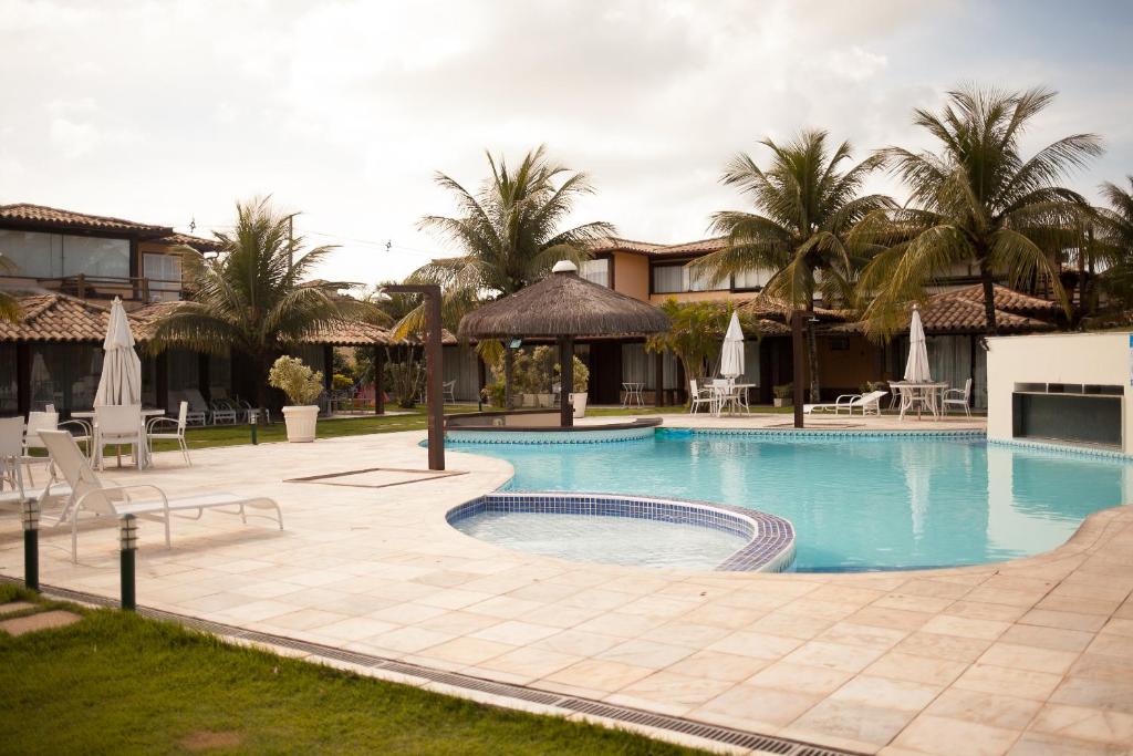 una piscina en un complejo con palmeras en Geribá Beach Apart Hotel apt504, en Búzios