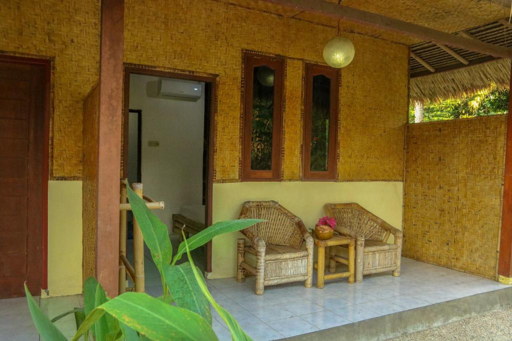 dos sillas de mimbre sentadas en el porche de una casa en Lendang Eco Lodge en Senggigi 