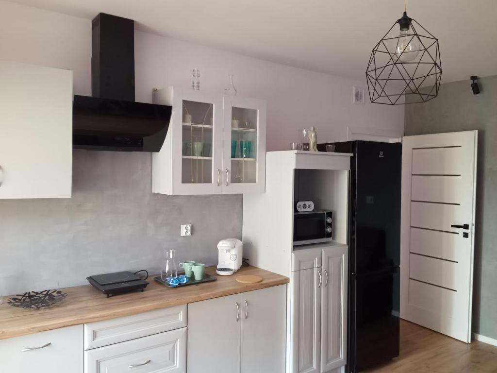 a kitchen with white cabinets and a black refrigerator at Ewela in Giżycko