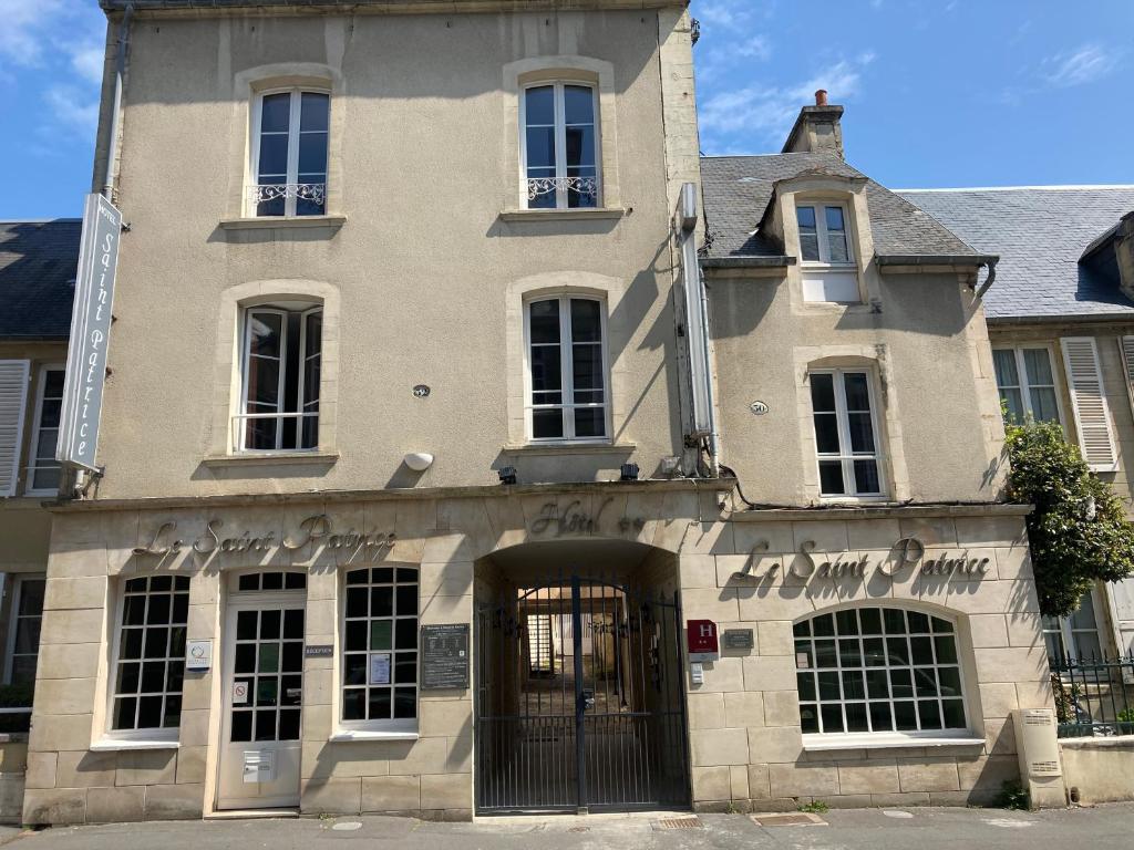 un vieux bâtiment avec une porte en face dans l'établissement Hôtel Le Saint Patrice, à Bayeux