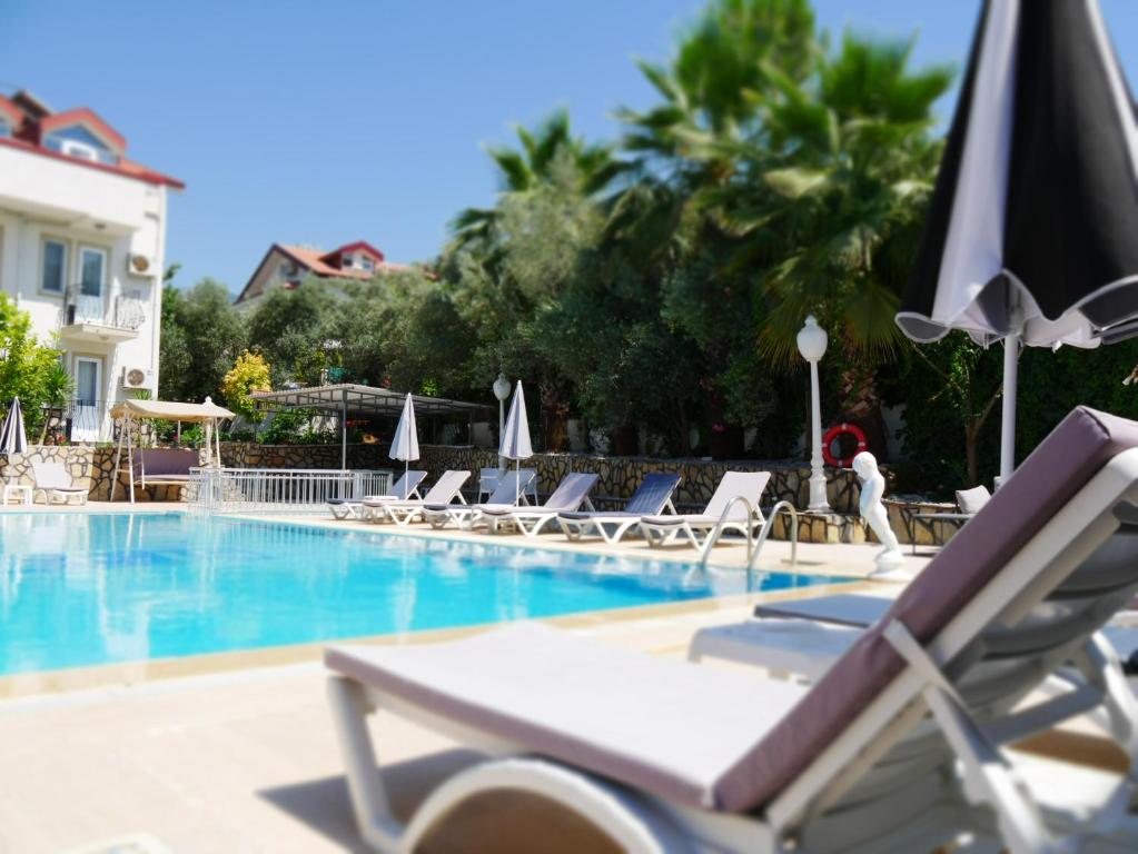 Nefis Hotel Ölüdeniz في أولدينيس: مسبح مع كراسي صالة ومظلة
