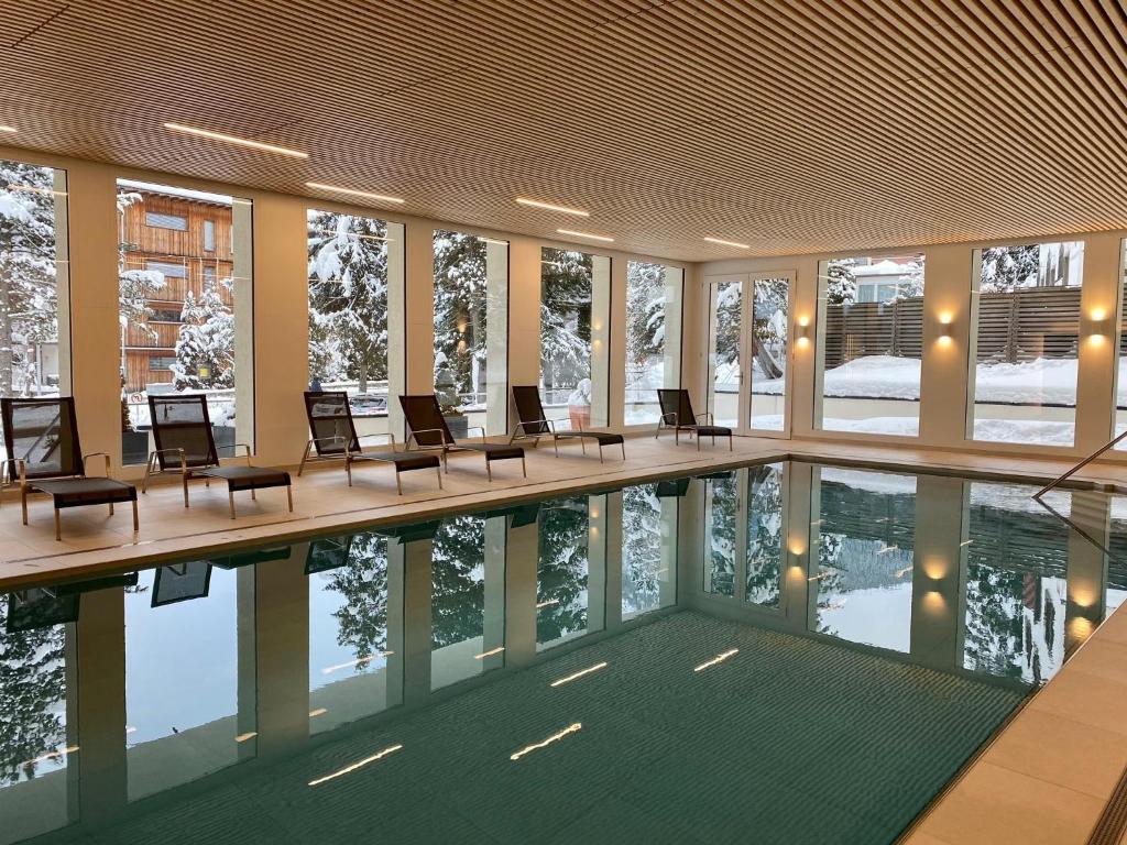 a swimming pool in a building with chairs around it at Hotel Meierhof in Davos