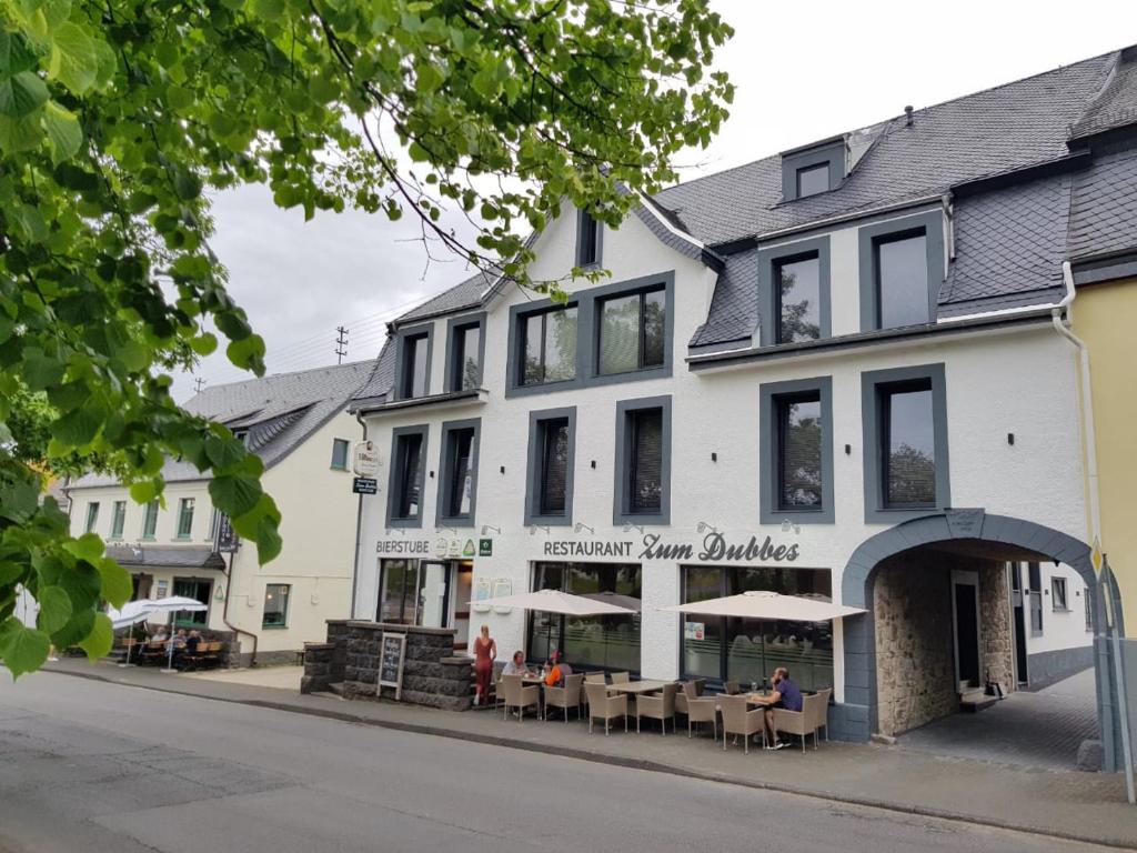 a white building with tables and chairs in front of it at 3H Hotels in Kelberg