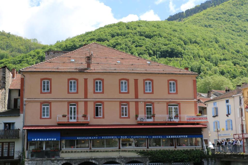 een groot roze gebouw voor een berg bij Hôtel Terranostra in Tarascon-sur-Ariège