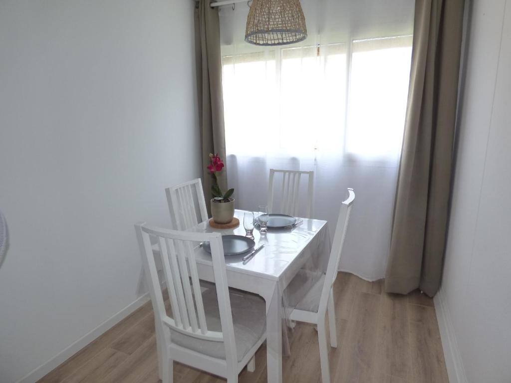 une table blanche et des chaises dans une pièce avec une fenêtre dans l'établissement Coquet Appartement T2, La Méditerranée, Narbonne Plage, à Narbonne-Plage