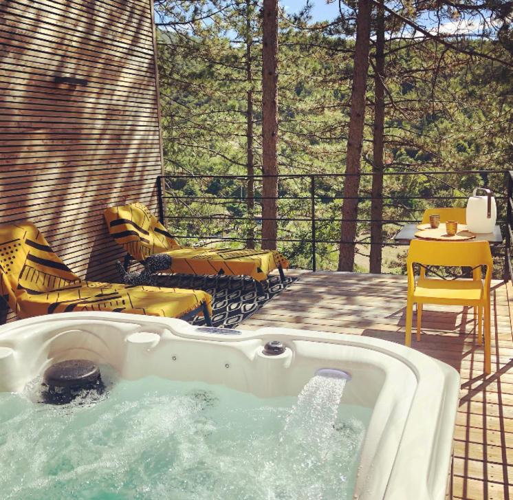 een hot tub op een patio met stoelen en een tafel bij La Parenthèse in Dieulefit