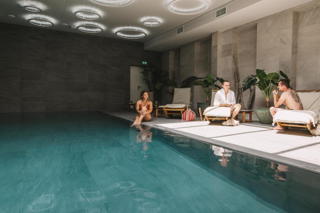 a group of people sitting around a swimming pool at Hôtel 1770 &amp; Spa in Le Pontet