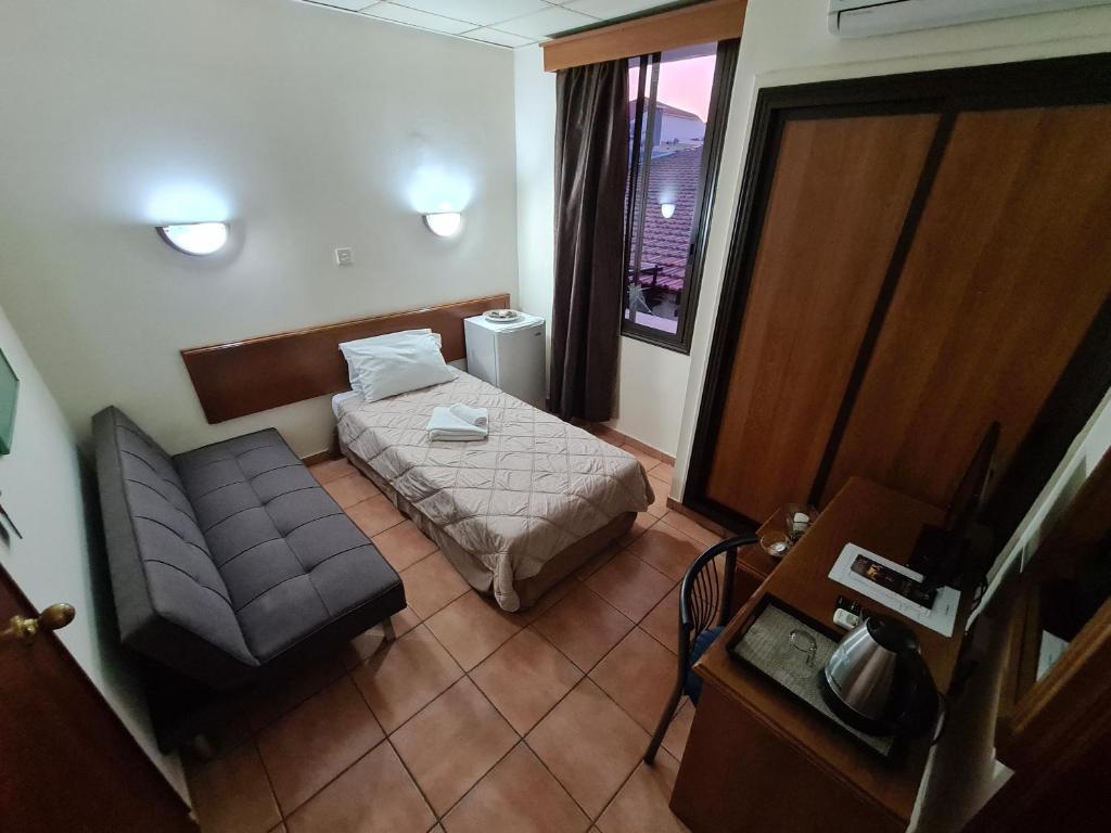 um pequeno quarto com uma cama e um sofá em Metropole Hotel em Limassol