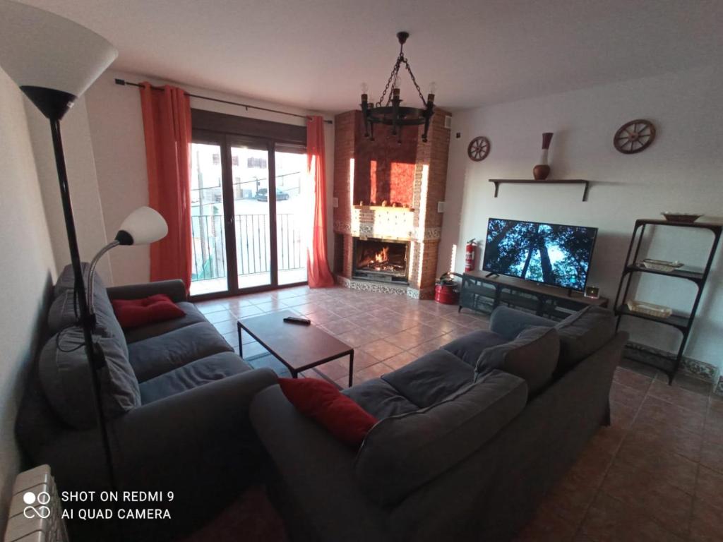 a living room with couches and a tv and a fireplace at Alojamiento Rural MAGALAN in Pozo Alcón