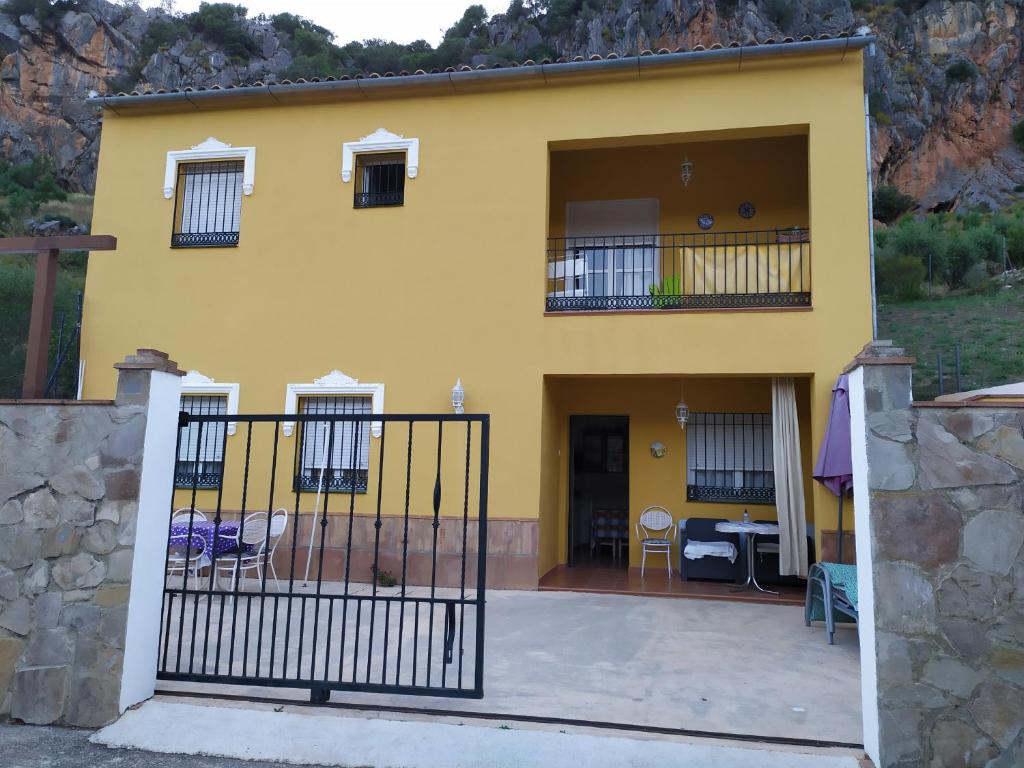 una casa amarilla con una valla delante en Apartamento El Serrano, en Benaoján