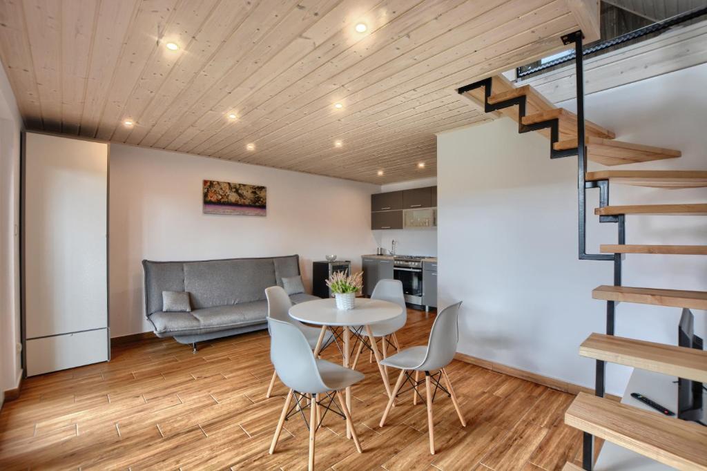 een woonkamer met een tafel en stoelen en een trap bij Guest House in Lesko