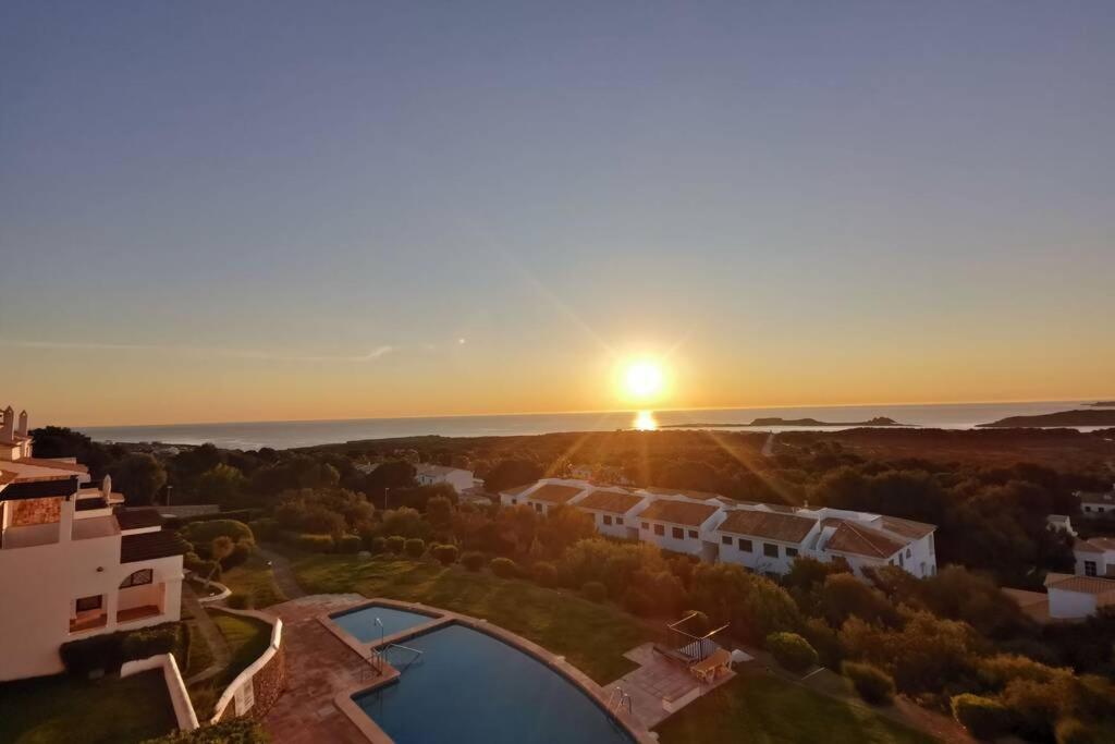 an aerial view of a house with the sunset in the background at V. Lona: beautiful duplex with a stunning seaview in Es Mercadal