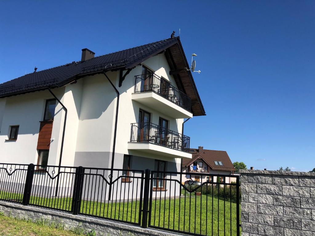 a white house with a black fence at Pokoje nad Morzem in Sztutowo