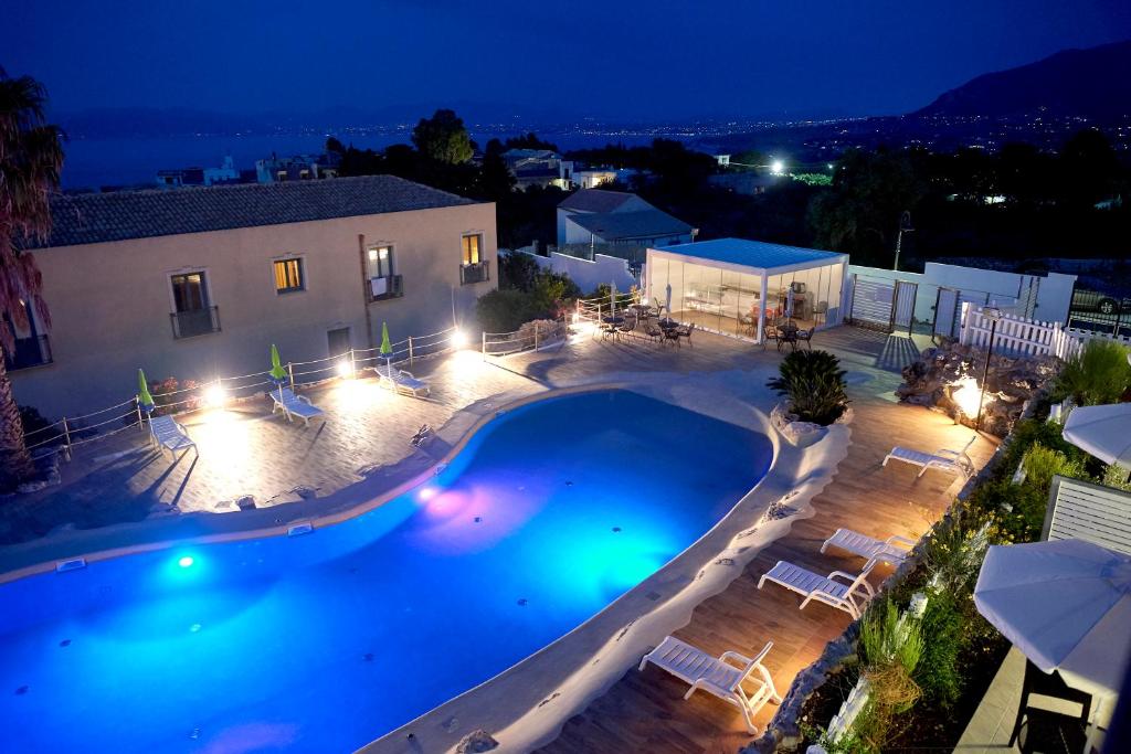 a large swimming pool in front of a house at night at Baglio Dello Zingaro in Scopello