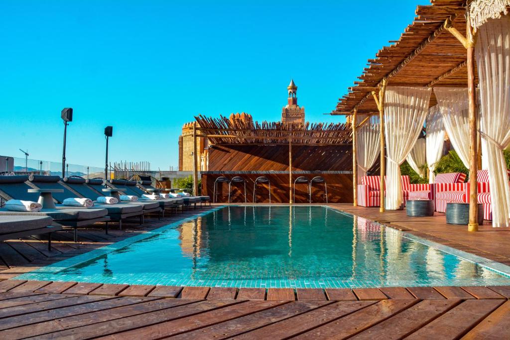 a swimming pool with chairs and a pavilion at NOW-VX adults only in Eilat