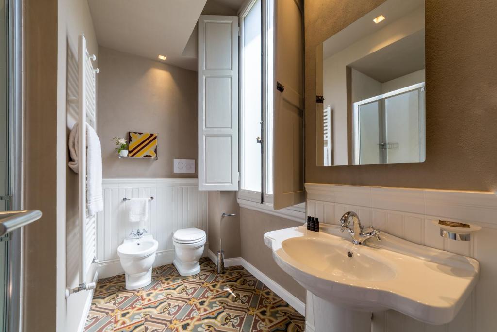 łazienka z umywalką, toaletą i lustrem w obiekcie Atelier delle Grazie we Florencji