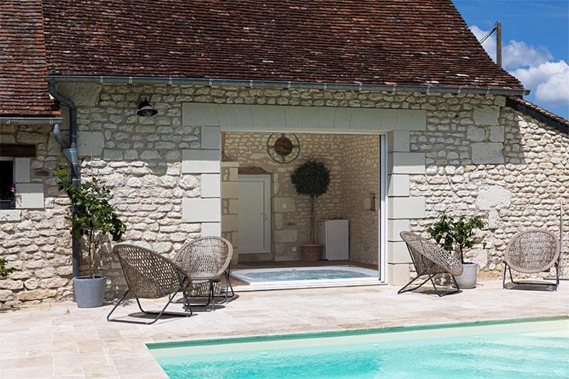 um pátio com cadeiras e uma piscina numa casa em la clef des champs em Lémeré