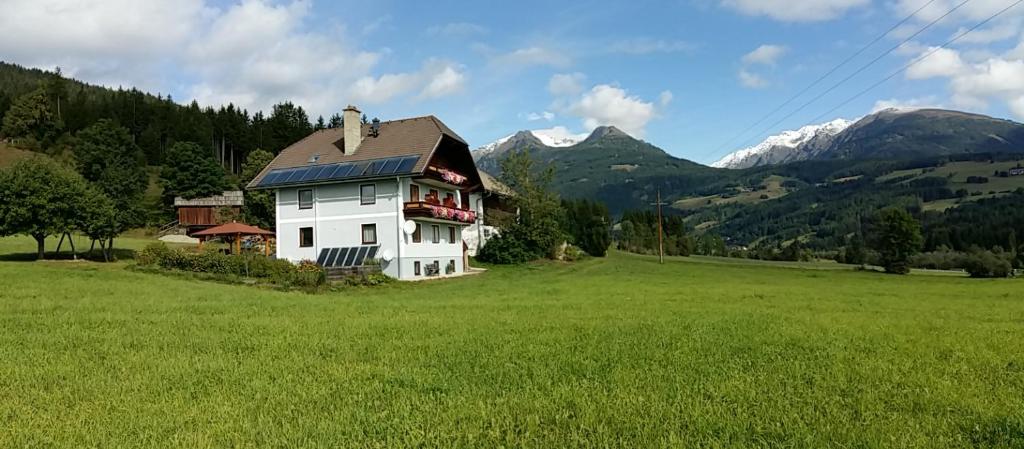 a white house in a field with mountains in the background at Ferienwohnungen Graggaber in Mariapfarr