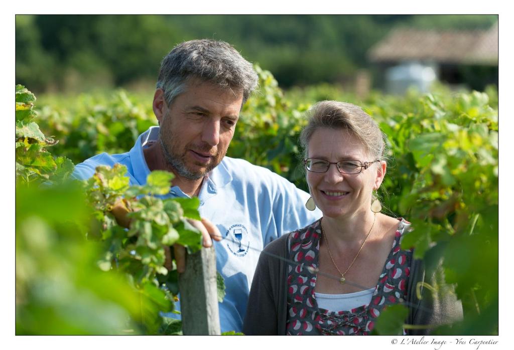 a man and a woman standing in a strawberry field at B&B Les Secrets de Tifayne in Puisseguin