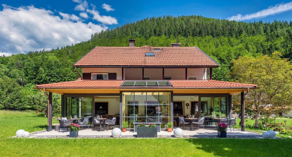 a house with a conservatory with a mountain in the background at Landgasthaus Kurz Hotel & Restaurant am Feldberg - Schwarzwald in Todtnau