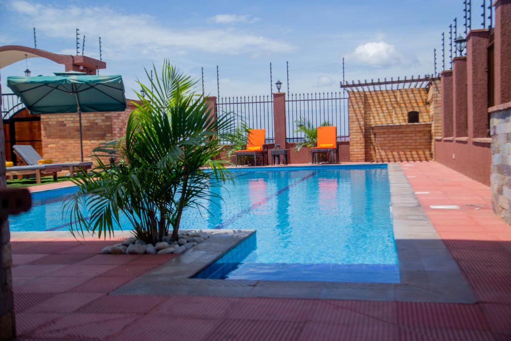 a swimming pool with a palm tree next to a building at Savannah Suites in Kampala