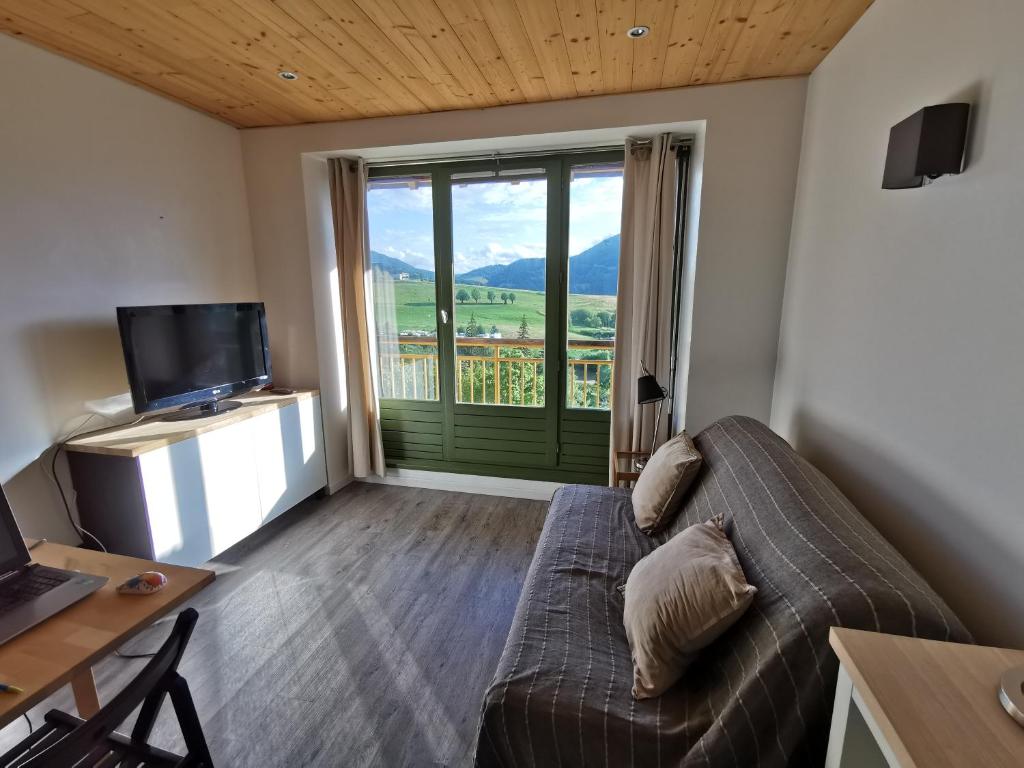un salon avec un canapé et une grande fenêtre dans l'établissement Appartement rénové pour 1p à 4p avec parking - Proche Centre, à Villard-de-Lans