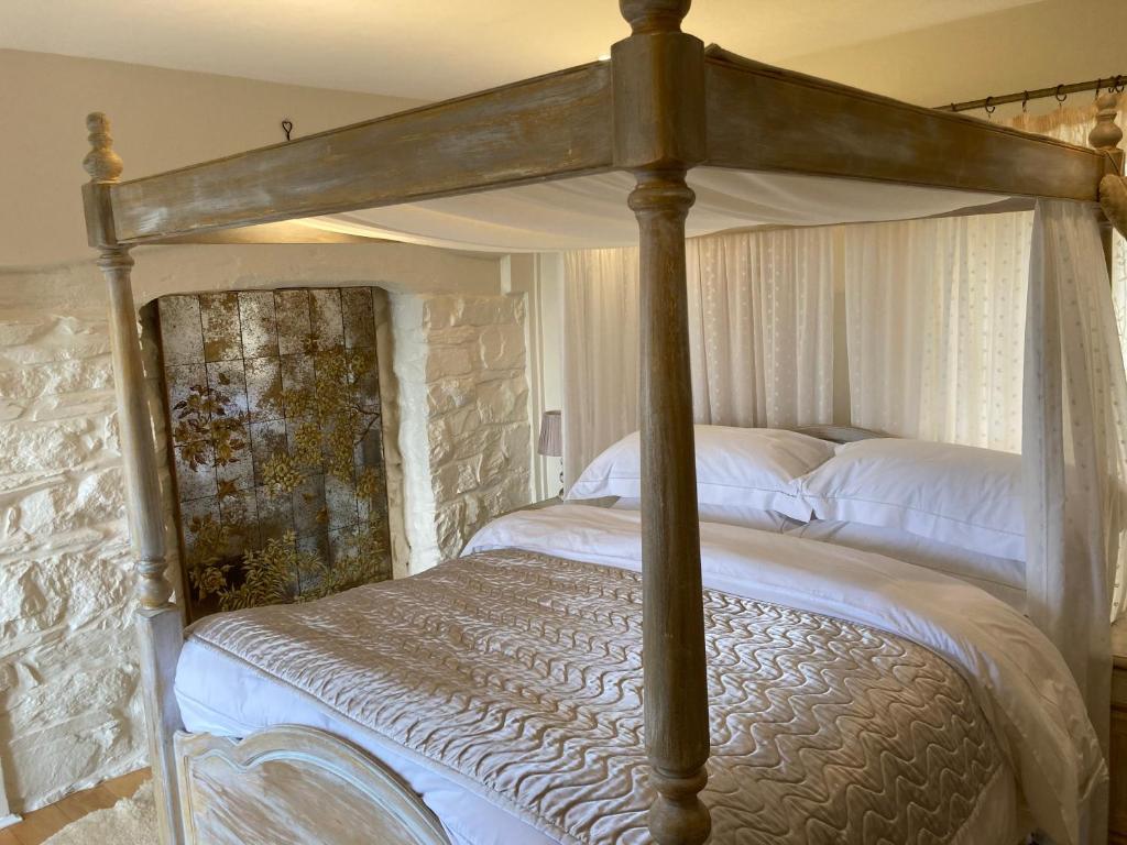 - une chambre avec un lit à baldaquin et des draps blancs dans l'établissement Snowdrop cottage @ Ty-llwyd, à Treffynnon 