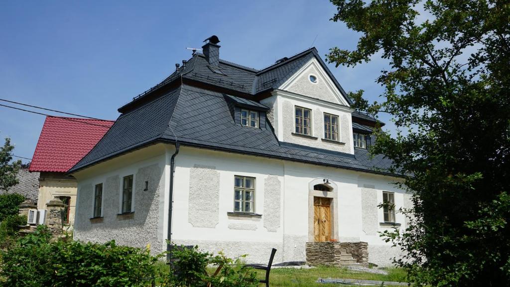 una casa blanca con techo negro en Barokní kaplanka 1796 A. D. - luxusní apartmány v Českém ráji, en Železný Brod