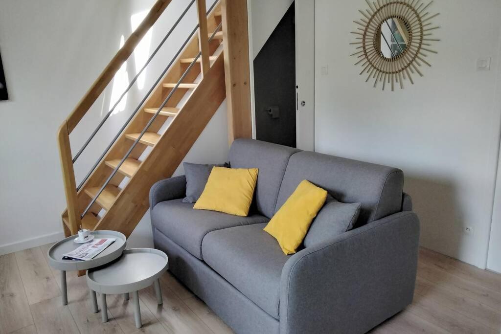 a living room with a gray couch with two yellow pillows at le studio du fou in Mortagne-sur-Sèvre