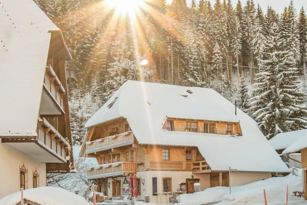 ein schneebedecktes Haus mit der Sonne im Hintergrund in der Unterkunft Holiday Apartements by Hotel Grüner Baum Feldberg in Feldberg
