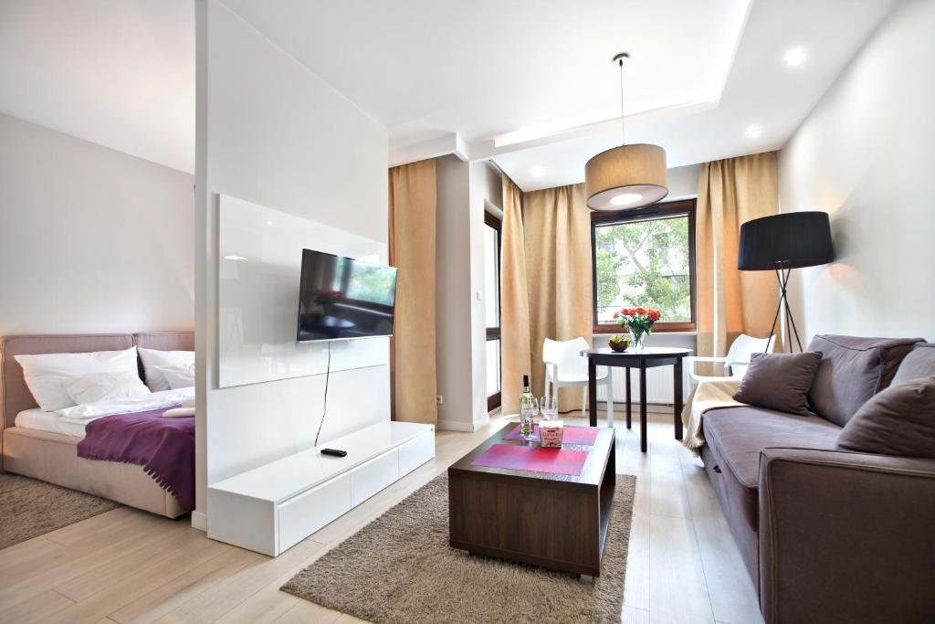 - un salon avec un canapé et une télévision dans l'établissement P&O Giełdowa Serviced Apartments, à Varsovie