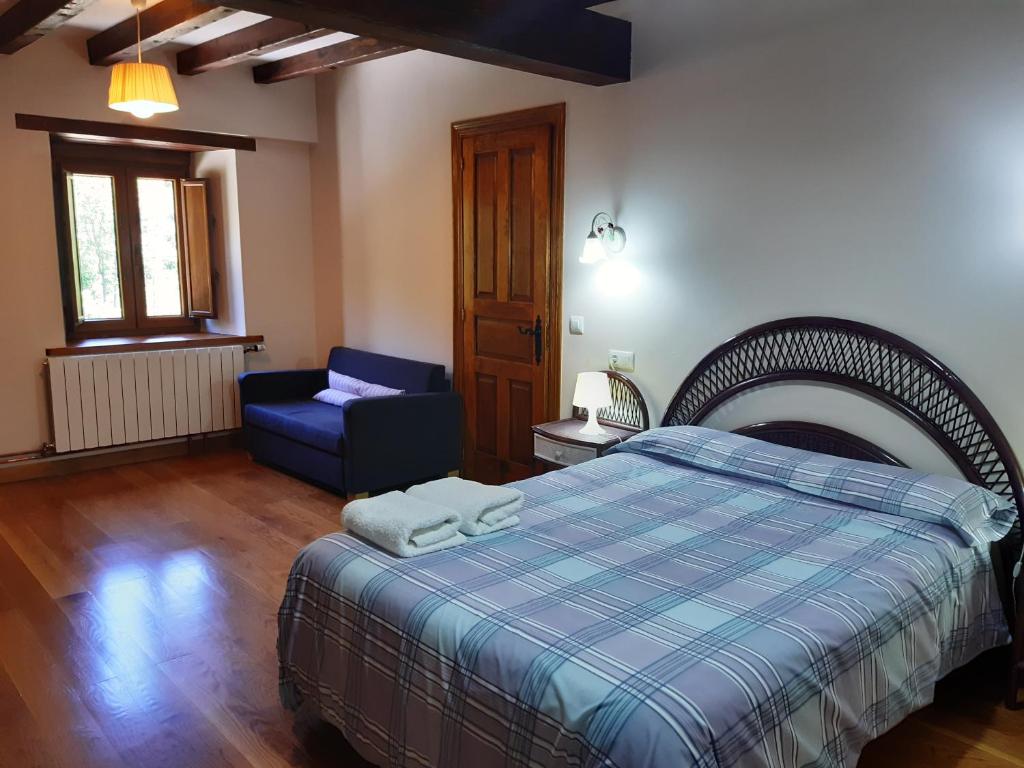 sypialnia z łóżkiem i niebieskim krzesłem w obiekcie Casa Santa Leocadia w mieście Tama