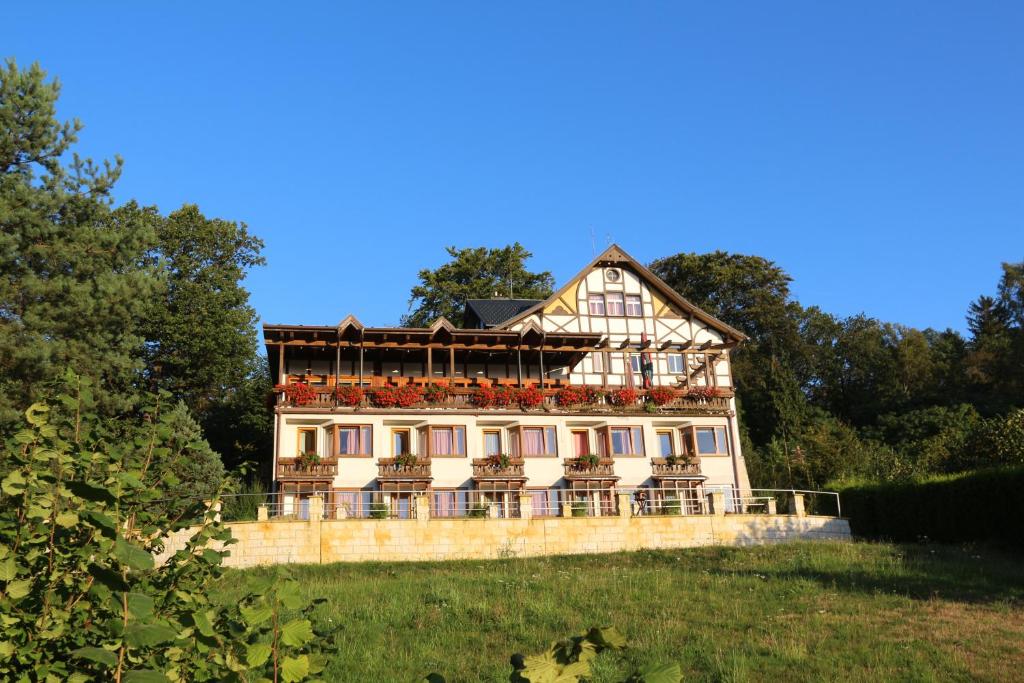 une grande maison avec balcon au-dessus d'un champ dans l'établissement Panoramahotel Wolfsberg, à Bad Schandau