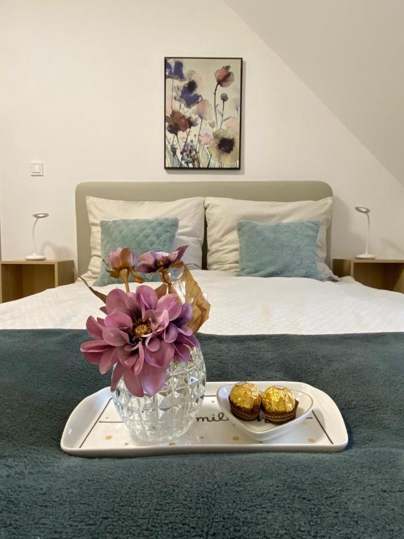 ein Tablett mit einer Vase aus Blumen und Keksen auf dem Bett in der Unterkunft Oázis apartmanház in Fertőszentmiklós