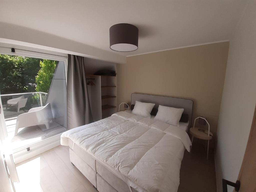 um quarto com uma cama branca e uma janela em Bee Tree Appartement em Vielsalm