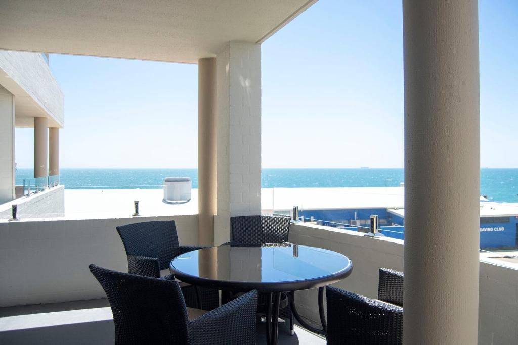 een tafel en stoelen op een balkon met uitzicht op de oceaan bij Cottesloe Beach View Apartments #7 in Perth