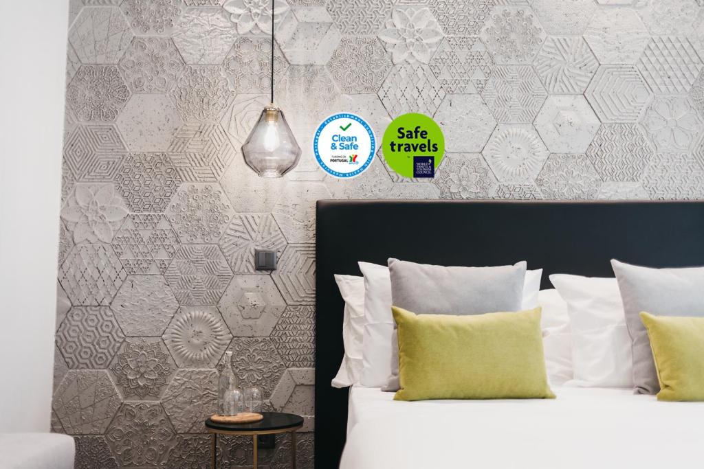 a bedroom with a bed with white sheets and a wall at &Tales Suites - Óbidos in Óbidos