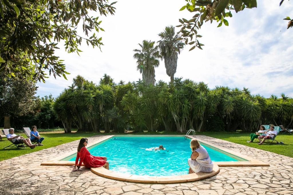 eine Gruppe von Menschen, die um einen Pool herum sitzen in der Unterkunft Masseria Baroni Nuovi in Brindisi