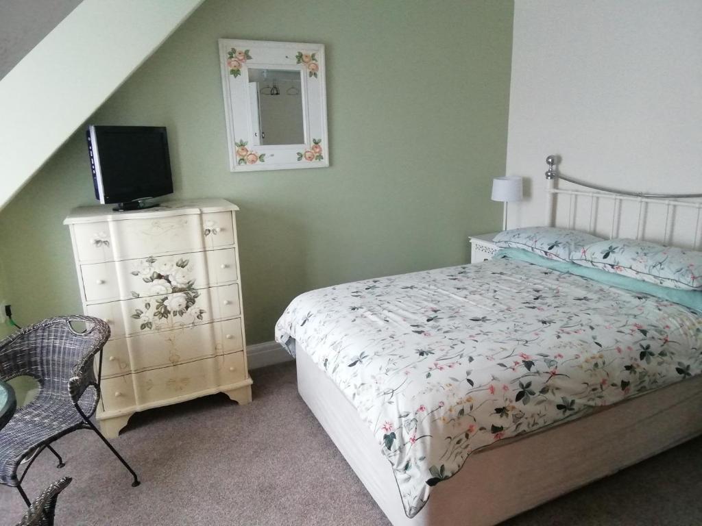 a bedroom with a bed and a dresser with a television at Railway Cottage in Swanage