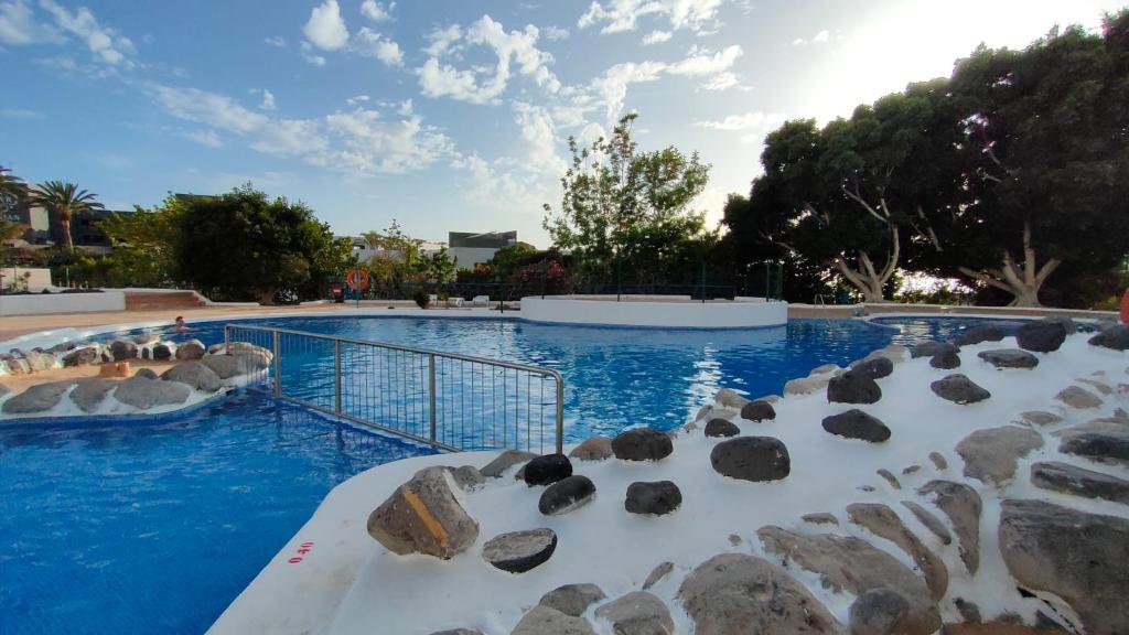 a swimming pool with blue water and rocks at Piera's Paraiso Seaview in Playa Paraiso