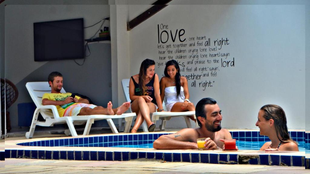 Che Lagarto Hostel Porto de Galinhas في بورتو دي غالينهاس: مجموعة من الناس يجلسون حول مسبح