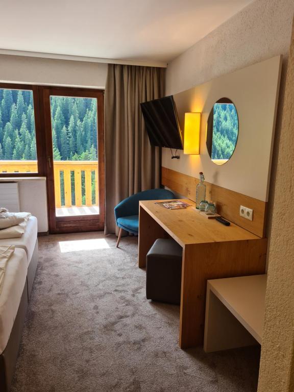 ein Hotelzimmer mit einem Schreibtisch, einem Bett und einem Fenster in der Unterkunft Hotel Zirbenhof in Hochfugen