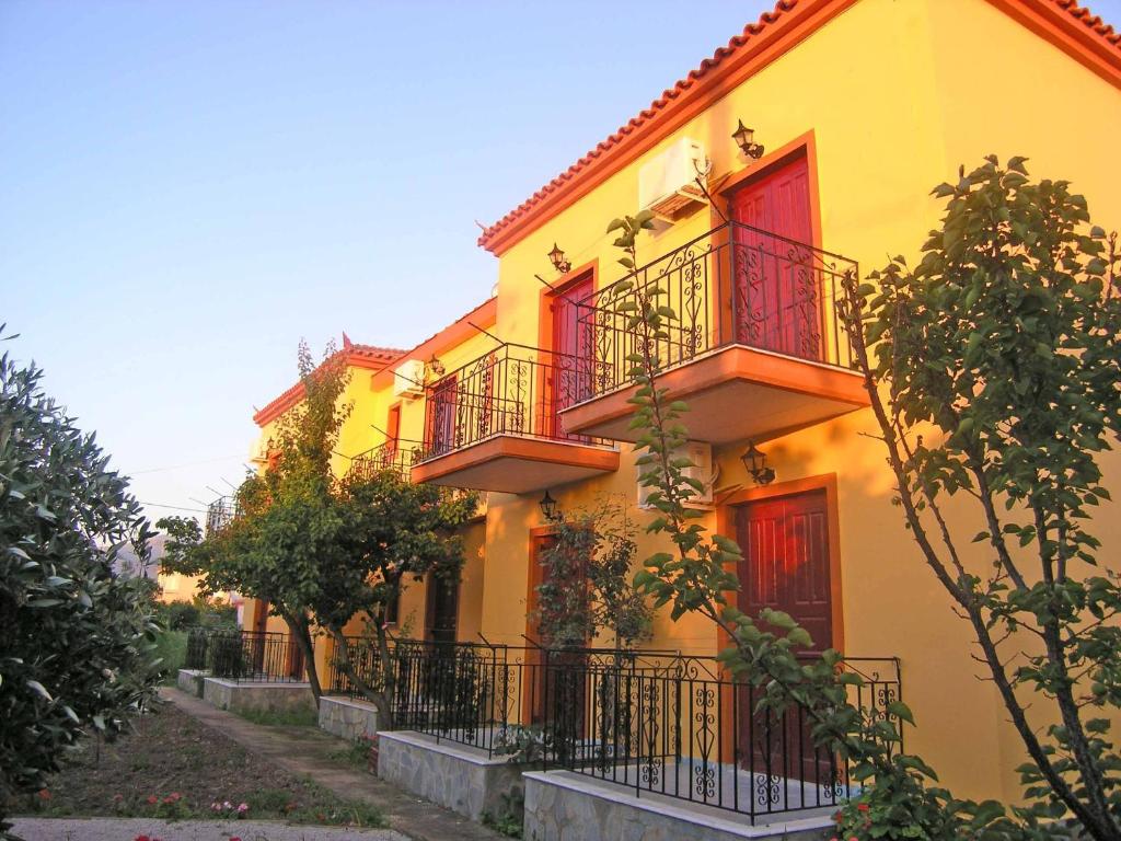 een geel gebouw met rode deuren en balkons bij Acapoulco apartments in Anaxos