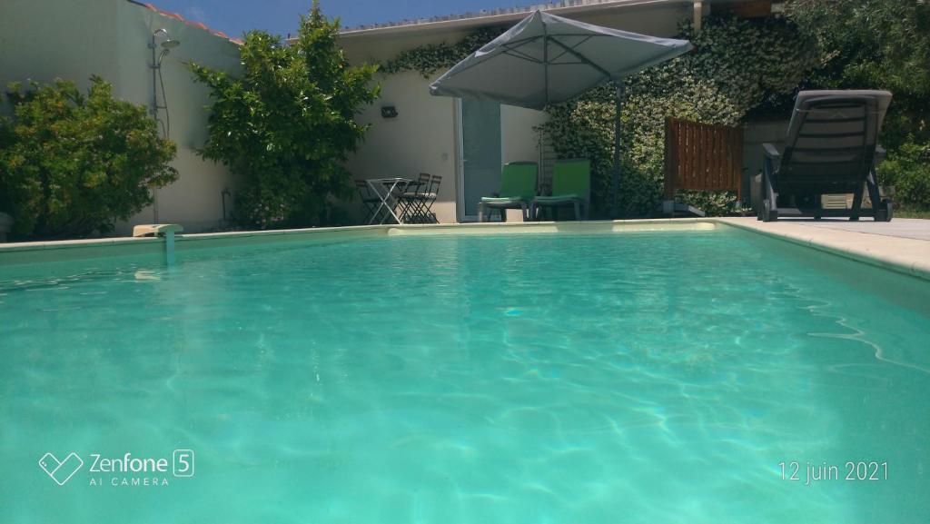 een zwembad met een parasol in de tuin bij Chambre direct piscine in Talence
