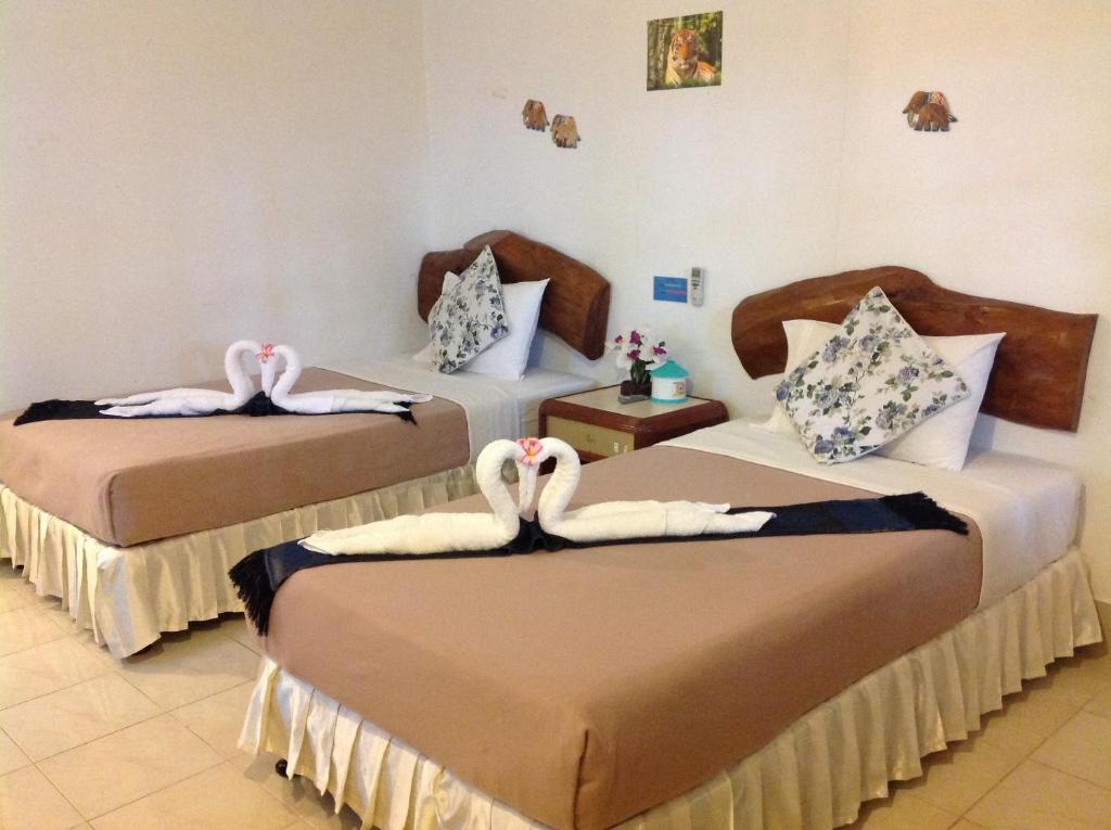 dos cisnes están sentados en dos camas en una habitación en Ruan Mai San Ngam Resort - SHA Plus, en Nai Yang Beach