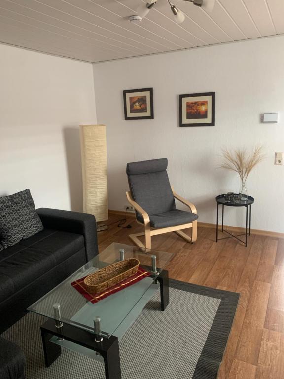 a living room with a black couch and a chair at Ferienwohnung Römmer in Ströbeck