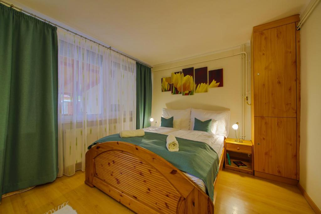 sypialnia z dużym łóżkiem z zieloną zasłoną w obiekcie Mária Apartman w Hajduszoboszlo