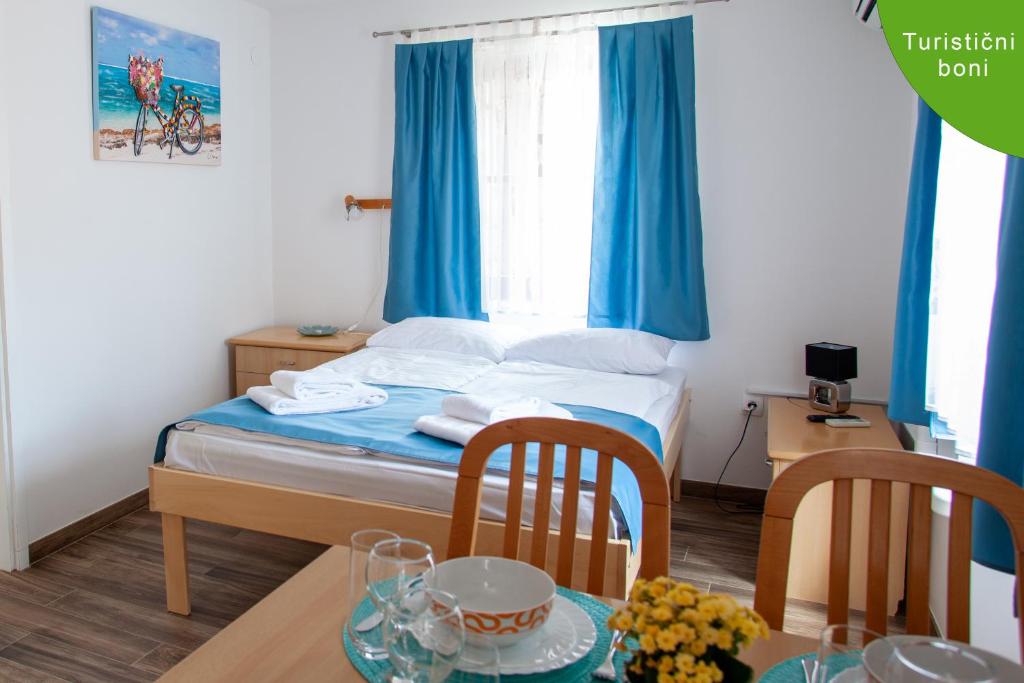 a bedroom with a bed with blue curtains and a table at Arcobaleno Apartments in Piran