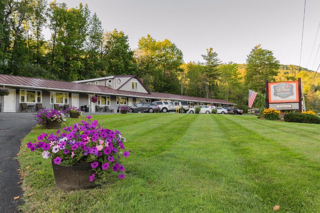 un bâtiment avec une grande cour ornée de fleurs violettes dans l'établissement Sleep Woodstock Motel, à Woodstock